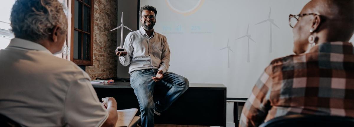 Man teaching two older people in a classroom, windmill in hand