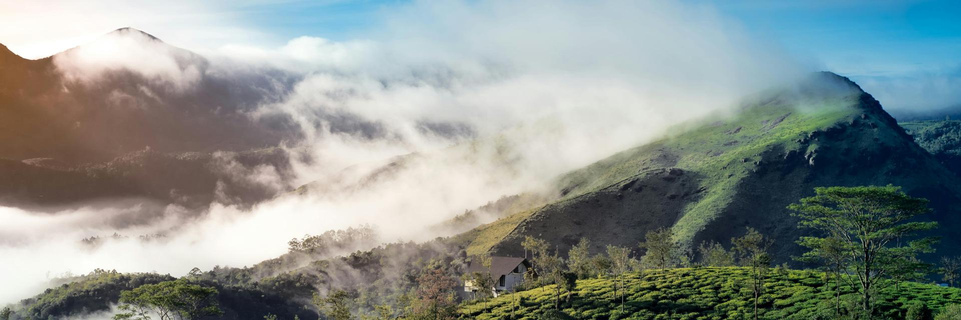 Green mountains with clouds and sun in the background