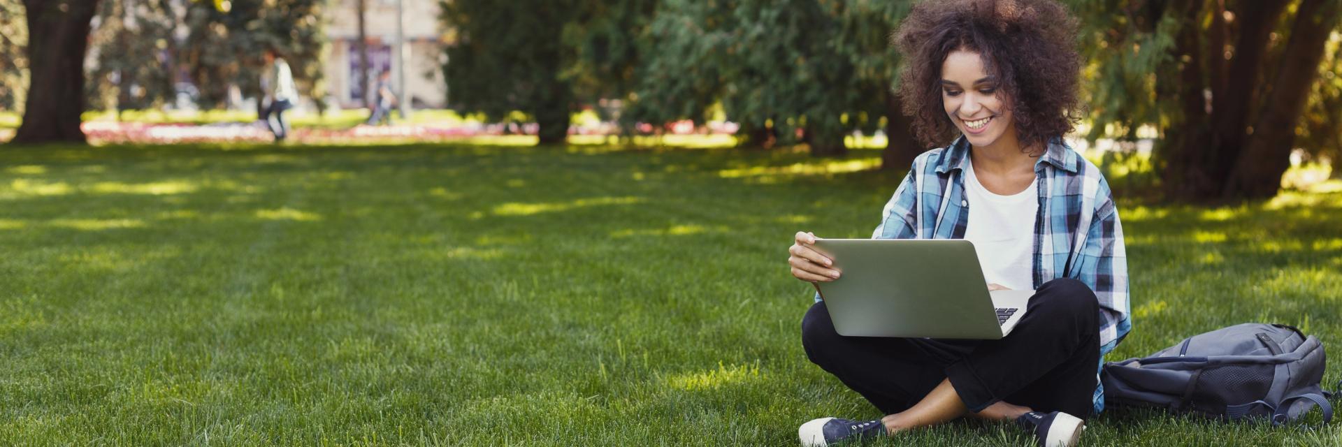 woman with laptop sitting in grass