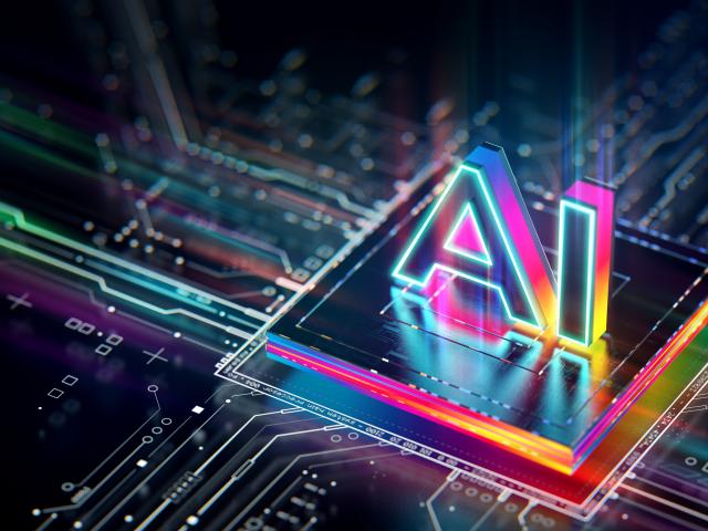 A computer chip lit with neon colors with "AI" in 3D letter on top of it