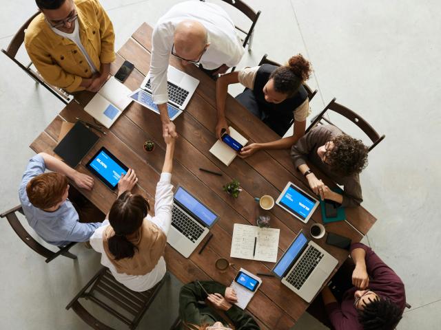 A group of people sitting at a table with laptops in front of them, bird's eye view