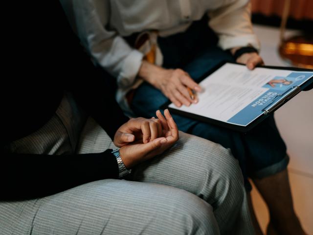 Two people sitting, looking over a digital resume displayed on a tablet