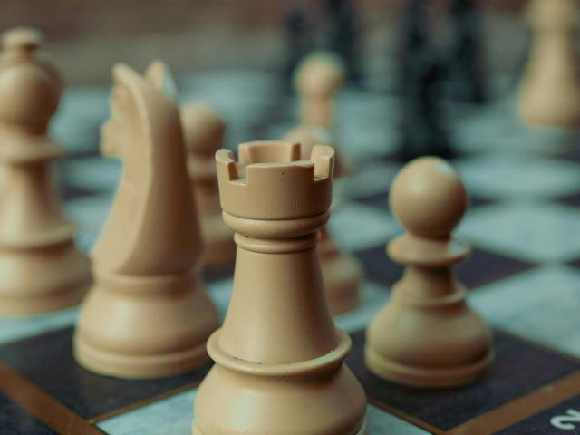 The view of a chess board from the corner, with tan and brown pieces set up