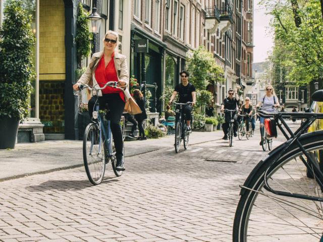 A woman riding a bicycle in a sunny Amsterdam