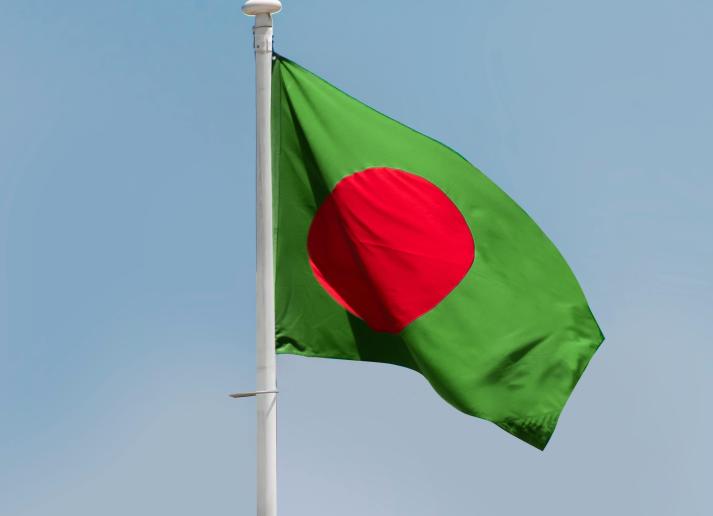 The flag of Bangladesh waving outside over a blue sky