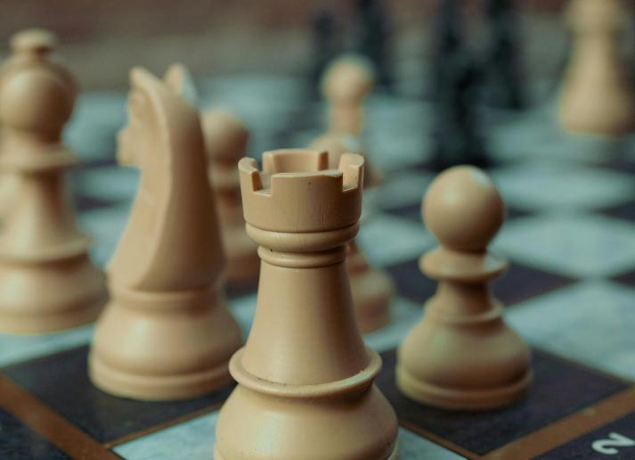 The view of a chess board from the corner, with tan and brown pieces set up