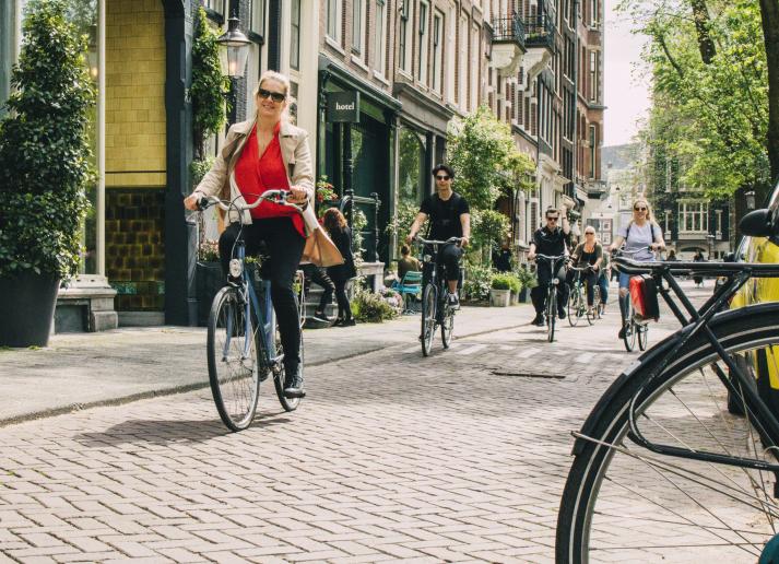 A woman riding a bicycle in a sunny Amsterdam