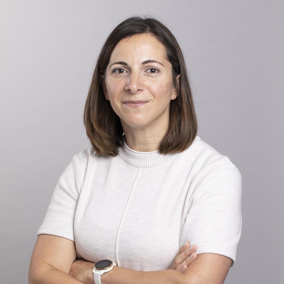 Woman smiling with arms crossed wearing white short sleeve shirt