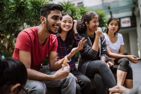 Group of students chatting and eating lucnh together outside
