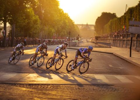Cyclists racing at sunset down a paved street