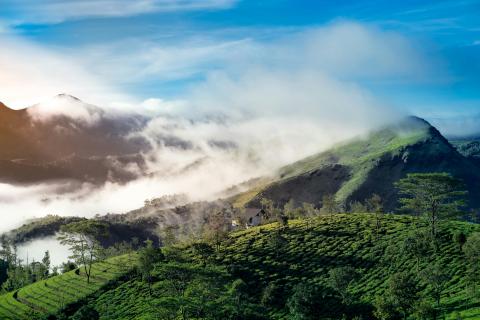 Green mountains with clouds and sun in the background