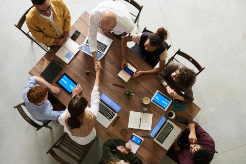 A group of people sitting at a table with laptops in front of them, bird's eye view