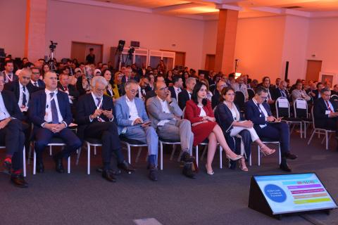 A crowd of people in a room listening to a panel 