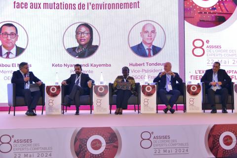 A panel of five people speaking at a conference 