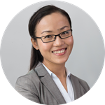 Susie Duong wears a gray suit jacket and glasses and is smiling at the camera