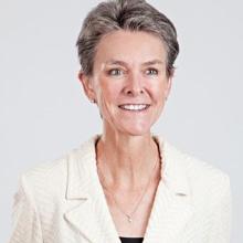 A woman in a white blazer with gray hair