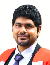 A man in a red blazer and a blue tie smiling at the camera