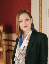 A woman standing wearing a printed scarf