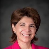 A women with brown hair and a pink shirt smiling